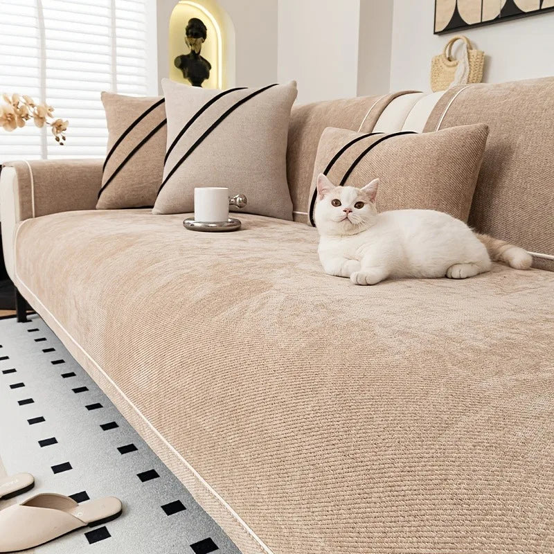 A beige chenille sofa protector cover with striped pillows and a white cat resting on the fabric.