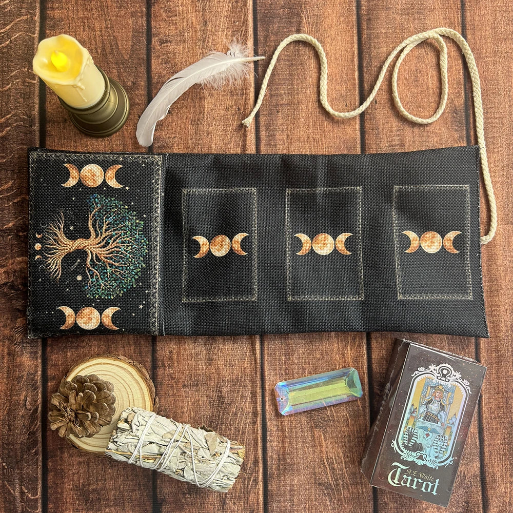 A black pouch for storing tarot cards with a tassel and a candle, next to a tarot deck.