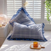 Two blue and gray plaid washed cotton pillowcases with ruffled edges resting on a white surface.
