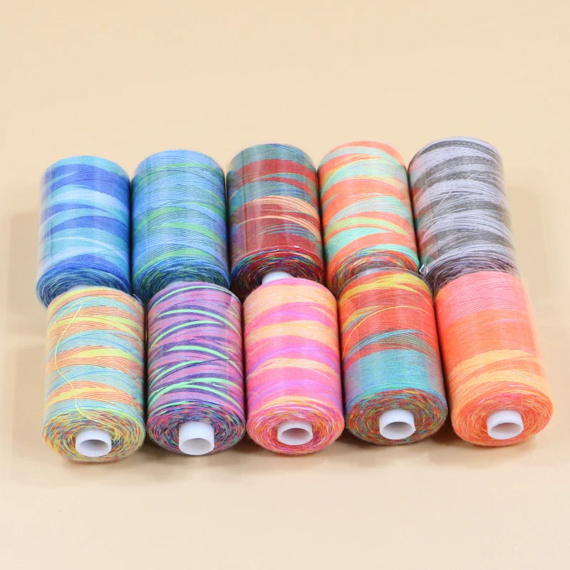 A collection of ten spools of brightly colored rainbow sewing thread arranged in a row.