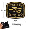 Black embroidery patch with gold lettering that reads Hecho en Mexico and features a hand print design.