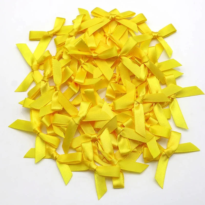 A pile of small yellow satin ribbon bows for crafts and decor.