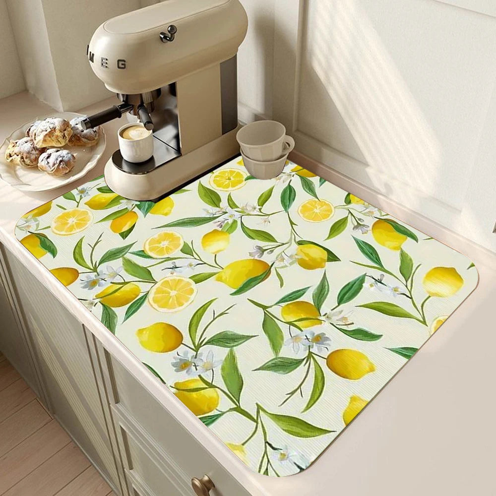 A yellow and green lemon printed non-slip dish drying mat placed on a kitchen counter next to a coffee maker.