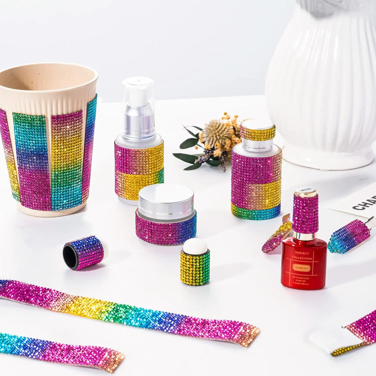 Assortment of iridescent crystal rhinestone ribbons and craft supplies displayed on a white surface.