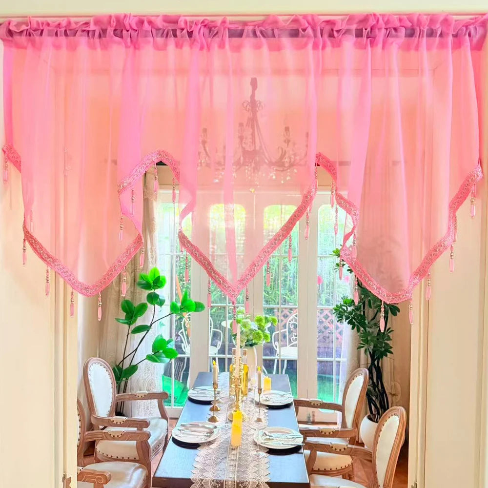 Pink sheer curtains with lace and tassels frame a window view.