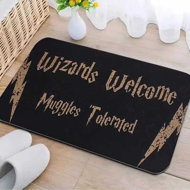 Black entrance mat with gold text reading Wizards Welcome Muggle Tolerated placed on a wooden surface.