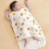 A baby is lying on a beige sleeping bag patterned with cute orange tiger faces and rainbows.
