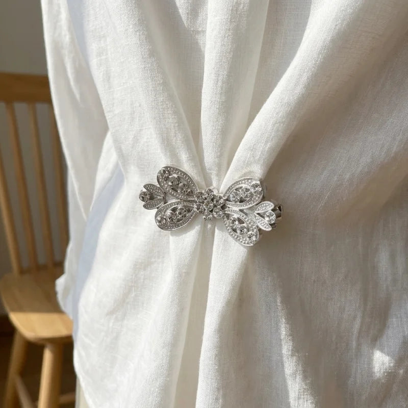 Elegant rhinestone clothing clips securing a white fabric scarf or garment
