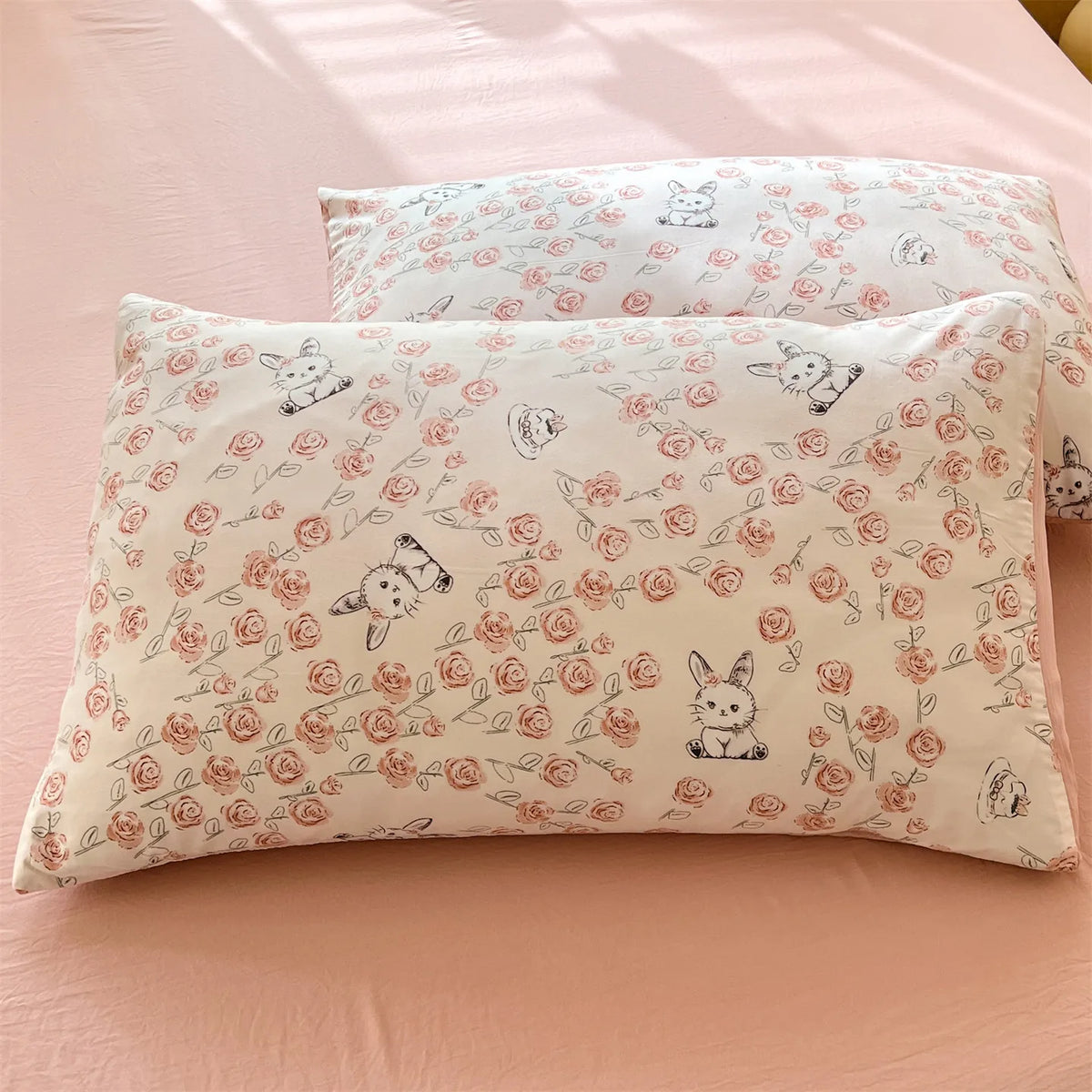 A close-up of a white floral printed pillow cover with small animal illustrations resting on a pink surface.