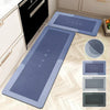A set of blue and gray diatom mud floor mats placed on a light wood floor next to kitchen cabinets.