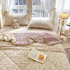 A light beige cartoon quilting comforter spread on a bed with white curtains and pillows.