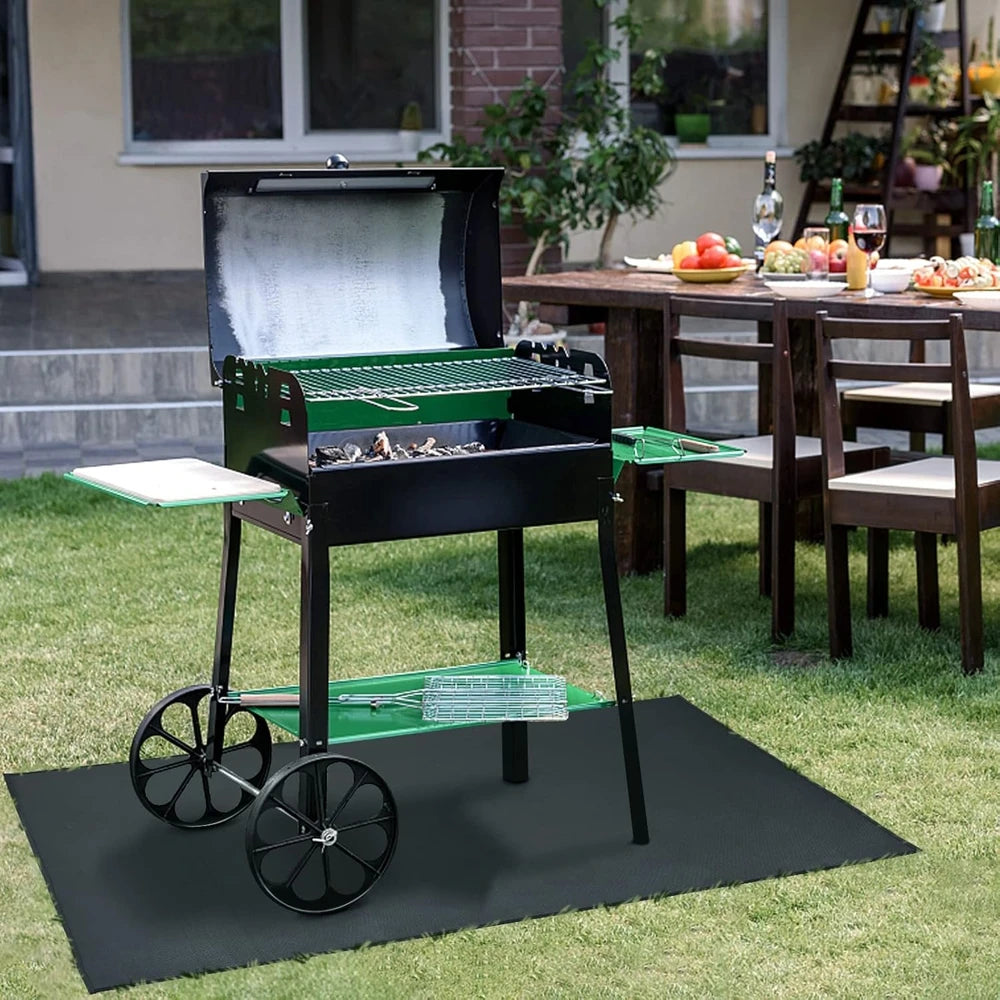 A black heavy-duty double-sided grill mat is placed on a dark mat outdoors on a lawn.