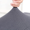 A hand is adjusting the fabric of a gray, textured elastic stool cover for living room seating.