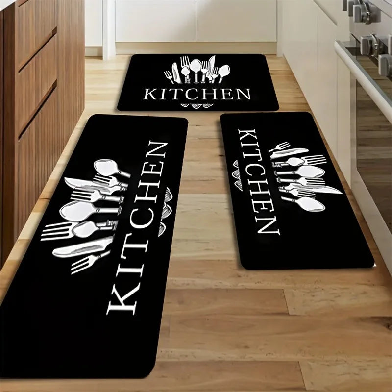 Black non-slip kitchen mats with white cutlery designs placed on a light wood floor.