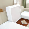 A white sofa seat protector cushion cover is shown on a beige sofa, featuring a textured pattern.