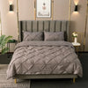 A gray quilted duvet and pillow bedding set displayed on a bed with a padded headboard.
