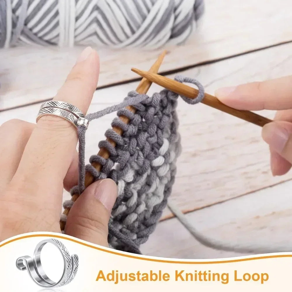 A hand is using a wooden stick to manipulate an adjustable knitting loop made of gray yarn.
