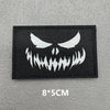 Black embroidered patch featuring a white demonic face design on a gray fabric background