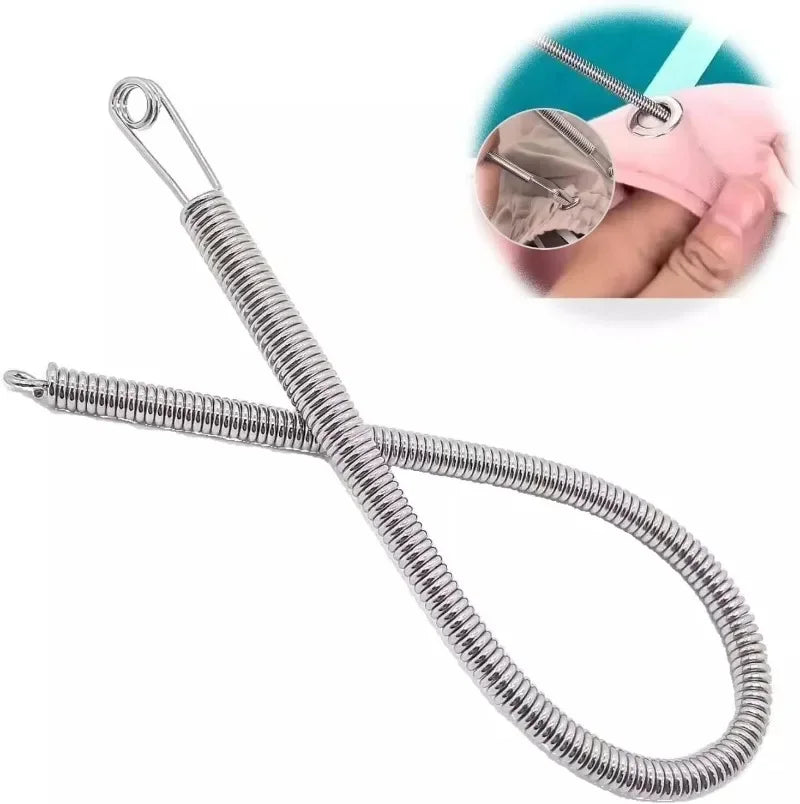 A silver spring drawstring sewing threader tool with a loop and a pink cloth demonstrating its use.