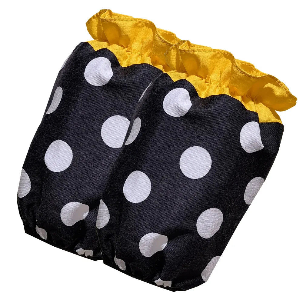 A black polka dot ruffle apron with yellow trim and pockets.
