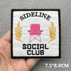 Black embroidered patch with white text SIDE LINE SOCIAL CLUB and pink chair and gold leaves
