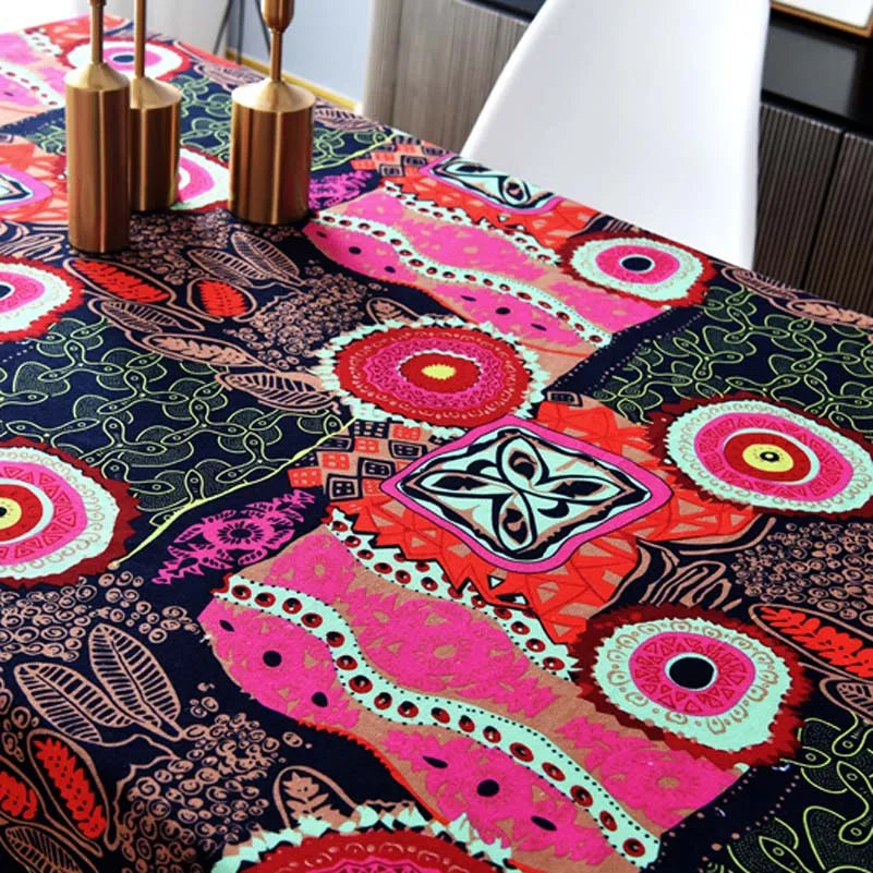 Close-up of a table covered with a vibrant bohemian printed linen fabric featuring pink, orange, and teal patterns.