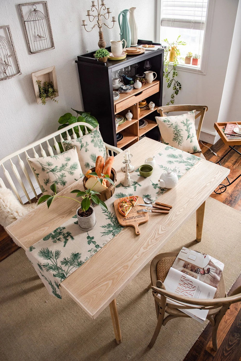 A light wood dining table set with a green and white patterned table runner, surrounded by natural decor.