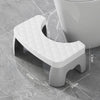 A white adjustable adult toilet squat stool with a diamond-patterned seat is shown on a gray tiled floor.