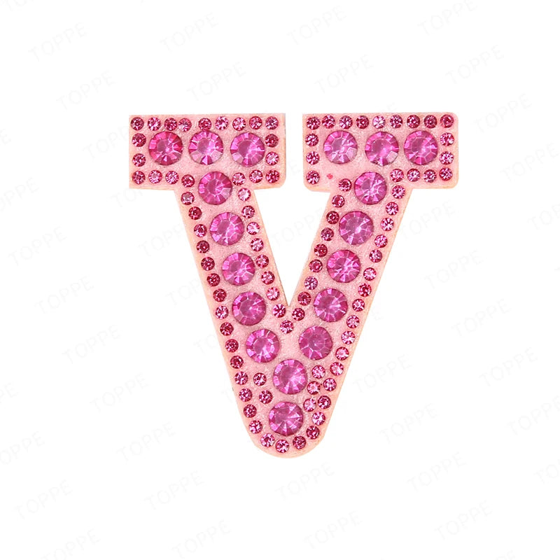 A large letter V made of pink and clear rhinestones used as a DIY patch.