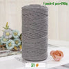 A roll of gray medium-thick hand-woven cotton yarn for crafting, next to a pink rose.