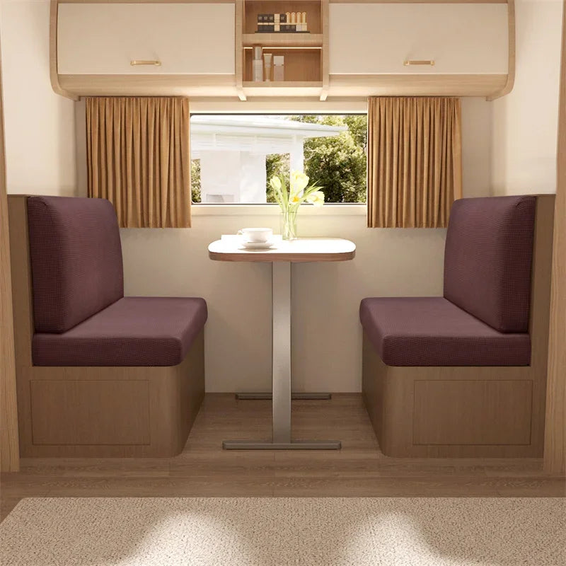 A modern interior featuring two upholstered chairs with light wood frames and neutral curtains facing a window.
