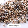 A pile of mixed geometric acrylic beads in various shades including gold, bronze, silver, and copper.