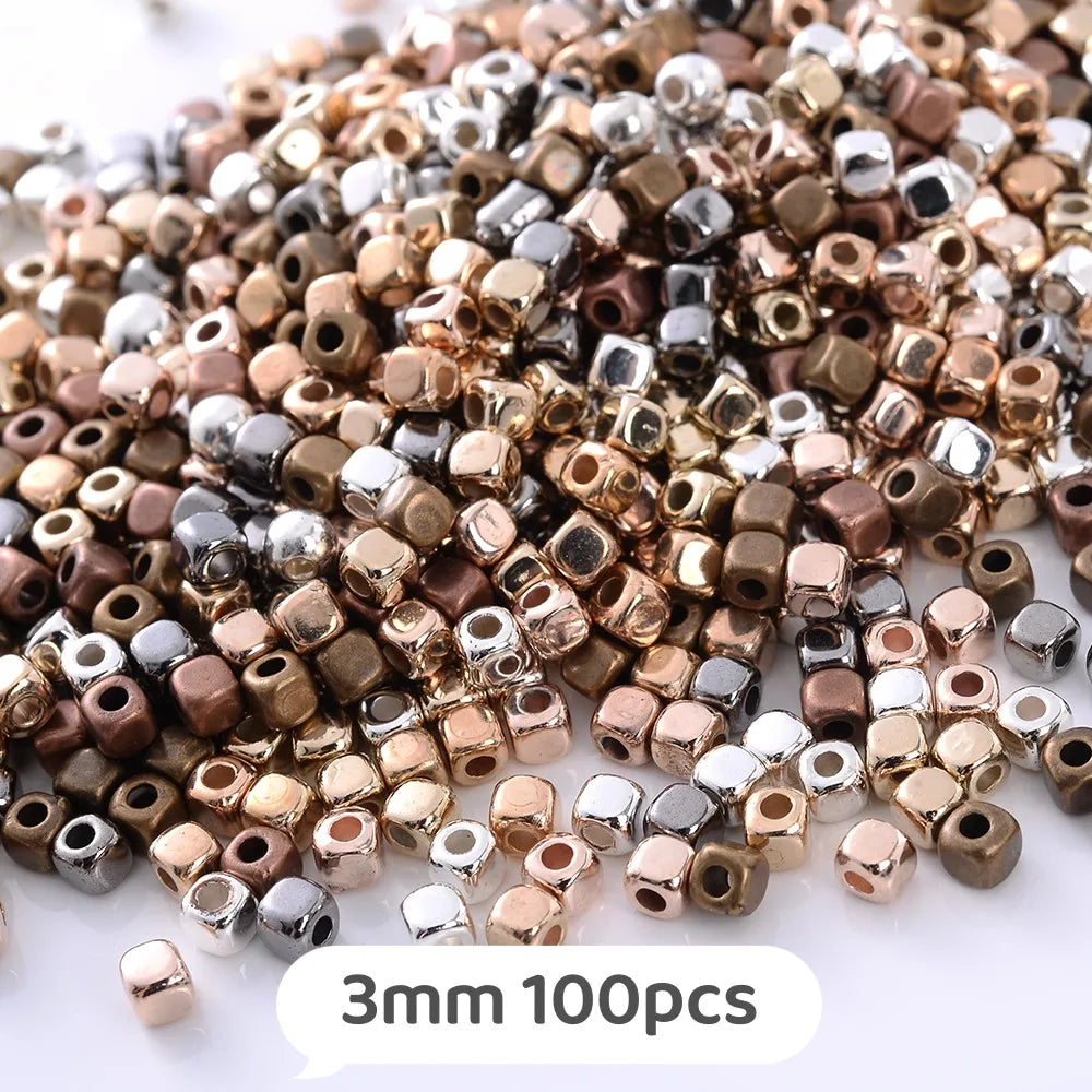 A pile of mixed geometric acrylic beads in various shades including gold, bronze, silver, and copper.