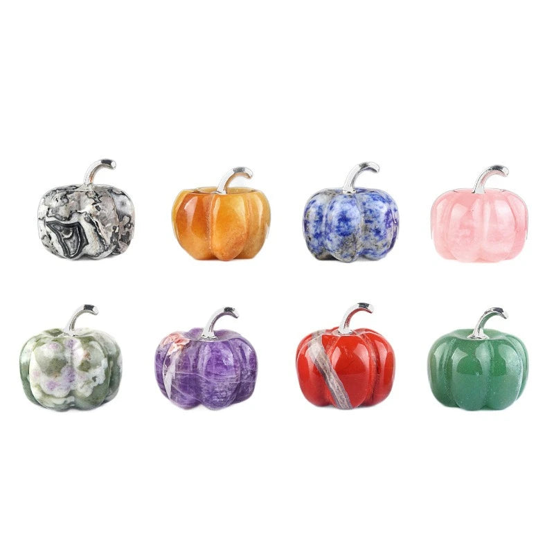 A collection of seven handcrafted gemstone colored pumpkin figurines in various shades including gray, orange, blue, pink, pu