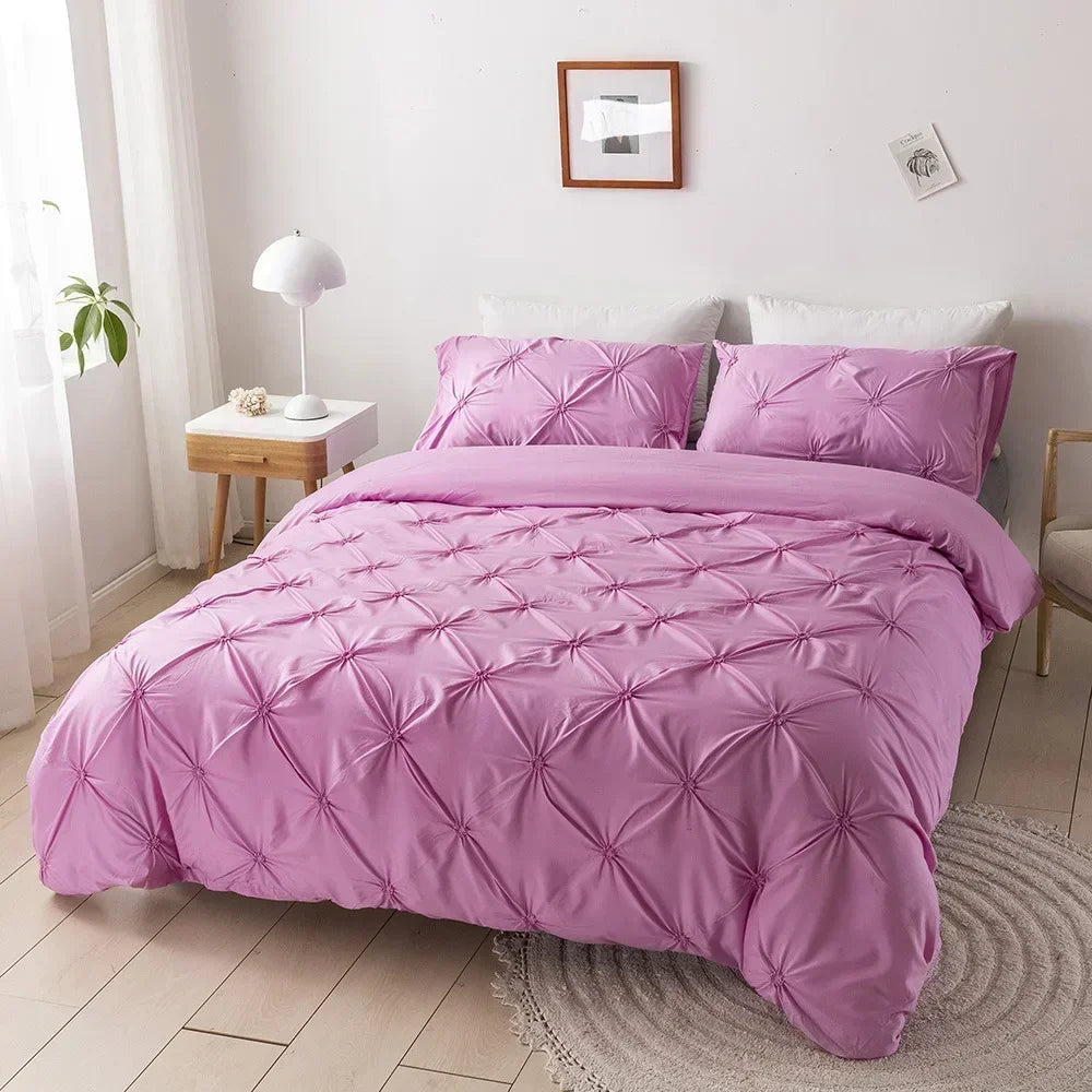A pink quilted duvet cover set displayed on a bed with white pillows and a wooden nightstand.