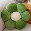 A plush sunflower flower cushion with green petals and a cream center resting on a light fabric surface.