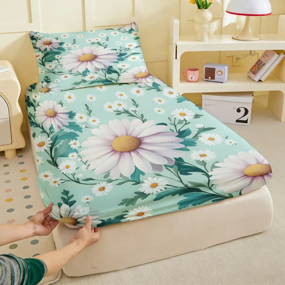A fitted mattress protector sheet with a white floral print featuring daisies and green leaves is displayed on a light-colore