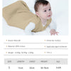A baby wearing a beige muslin cotton sleeping bag or swaddle.