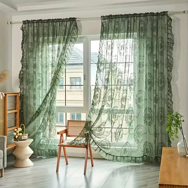 A pair of sheer green lace floral window curtains hanging in a bright room.