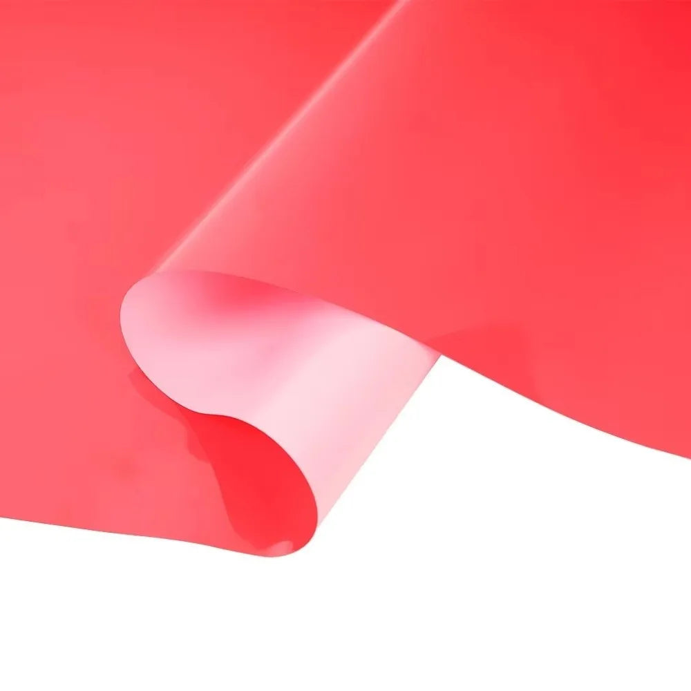 A sheet of red heat transfer vinyl being folded or rolled, showing a smooth, glossy texture.