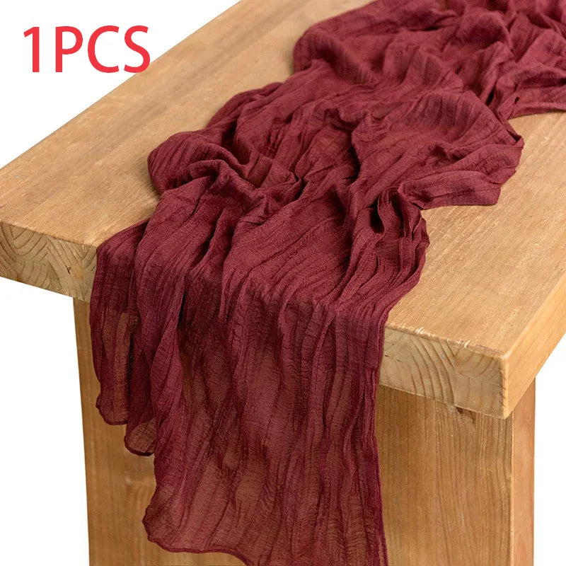 A deep maroon semi-sheer gauze fabric draped over a wooden table surface.