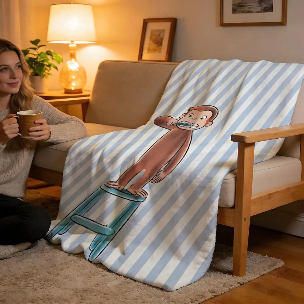 A striped throw blanket featuring a C-Curious George character on a light beige sofa.