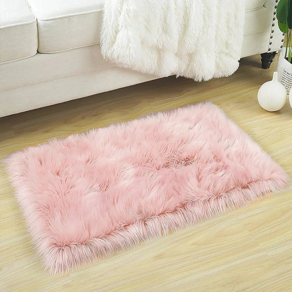 A fluffy pink faux fur floor rug placed on a light wood floor next to a white sofa.