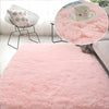 A fluffy pink area rug with a soft texture is displayed in a bright room setting.