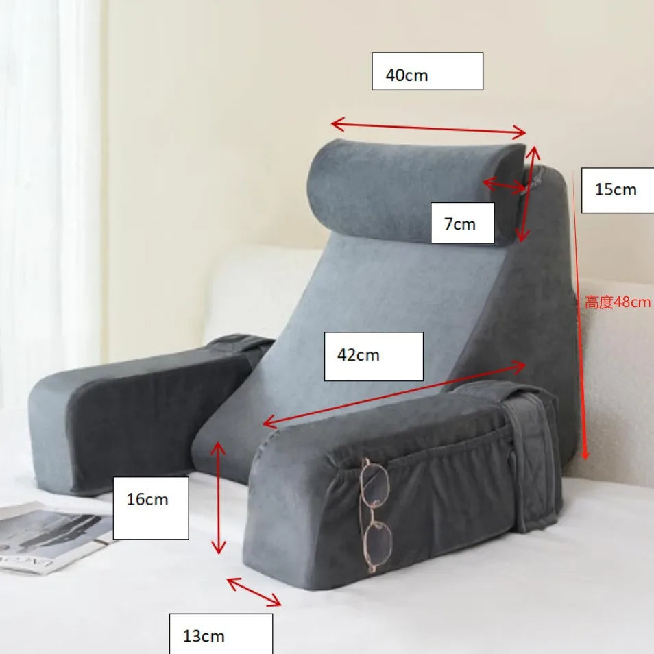 Gray ergonomic back support pillow with armrests shown on a bed.