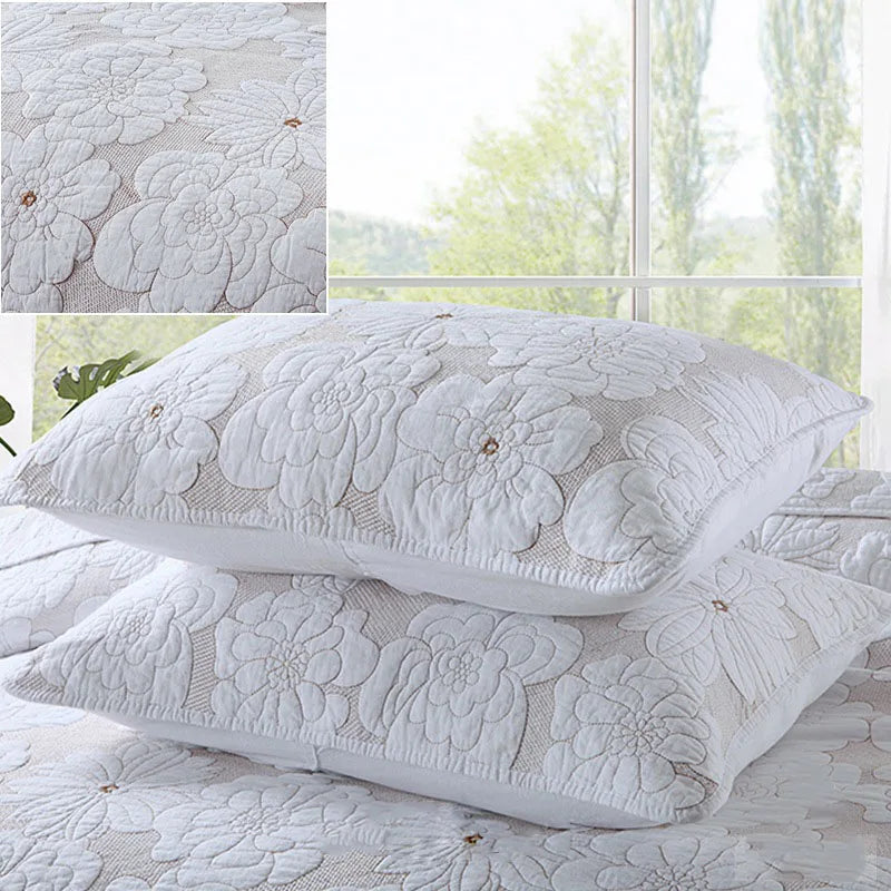 A set of white embroidered cotton quilted pillow covers featuring a floral pattern.