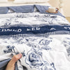 A close-up of a white duvet cover featuring a blue floral pattern and embroidered text on a bed.