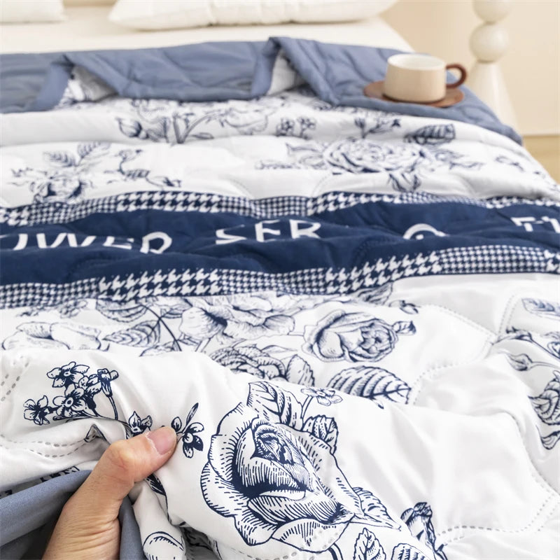 A close-up of a white duvet cover featuring a blue floral pattern and embroidered text on a bed.