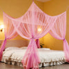Pink mosquito net bed canopy draped over a white bed in a yellow room.
