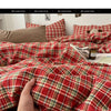 A close-up of a red and green plaid duvet cover set being held by a hand.